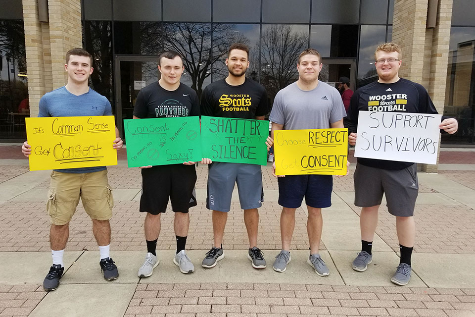 Young Men volunteering and holding signs supporting women's consent